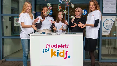 Studentinnen von students vor kids lachen und werden Karten in die Luft; Foto: evdus